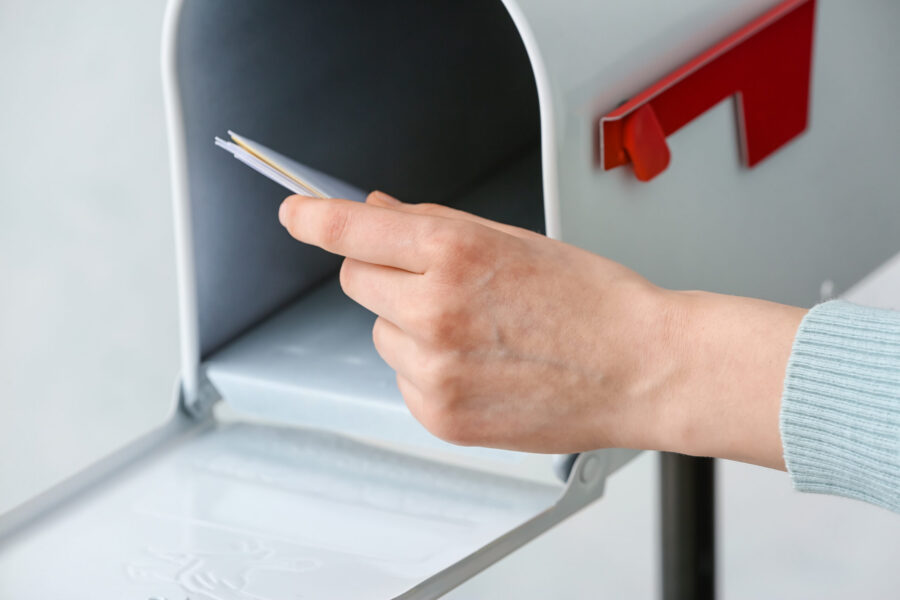 Woman getting letters from box on light background